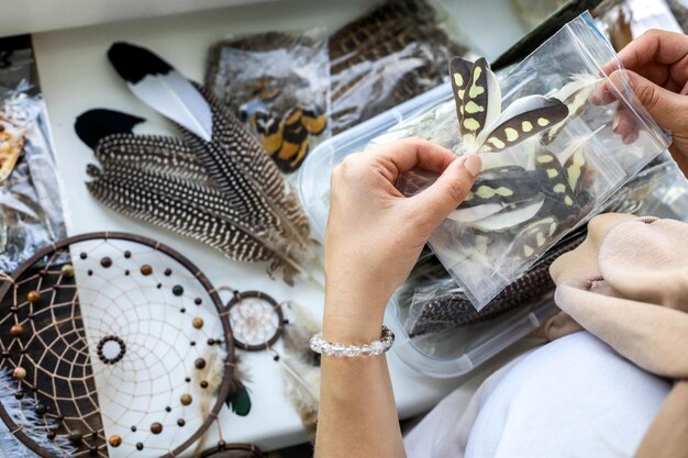 Vista superior de las manos de la mujer artística creando atrapasueños, amuleto nativo tribal, uso de plumas naturales