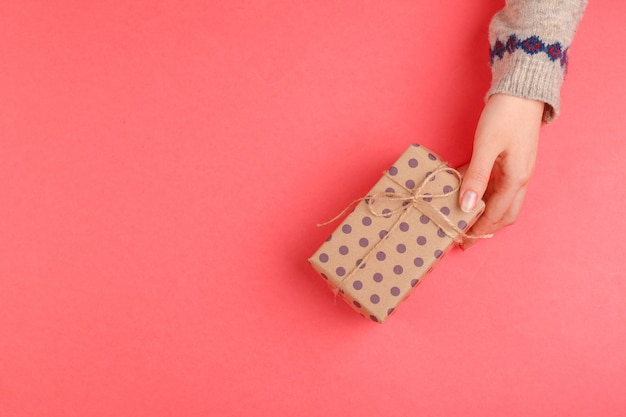 Vista superior de manos de mujer con caja de regalo en rosa