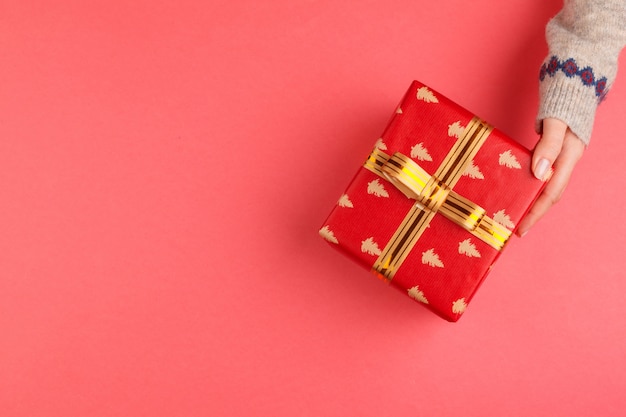 Vista superior de manos de mujer con caja de regalo sobre fondo rosa