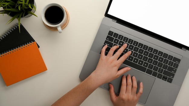 Vista superior de las manos de una mujer escribiendo en el teclado de la computadora portátil moderna en su escritorio de oficina.