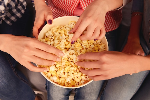 vista superior de las manos de las mujeres tomando palomitas de maíz