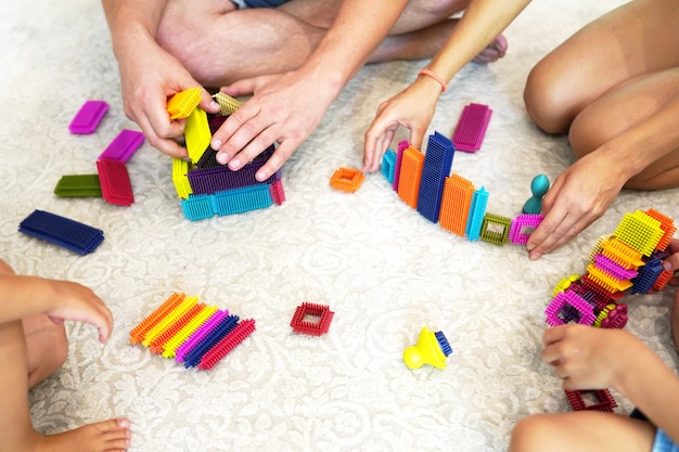 Vista superior en las manos del niño y de los padres jugando con coloridos ladrillos de plástico.