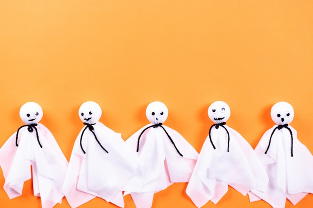 Foto vista superior de las manualidades de halloween, fantasma de papel sobre fondo de papel naranja con copyspace