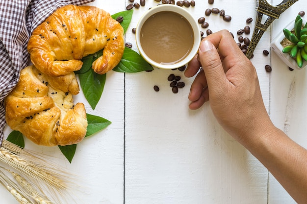 vista superior mãos de homem comendo café e croissant com grão de café