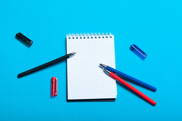 Vista superior maqueta del espacio de trabajo sobre fondo azul con cuaderno, bolígrafo