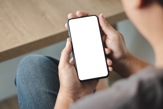 Vista superior maquete de imagem mão usando um homem smartphone segurando o telefone celular com tela em branco