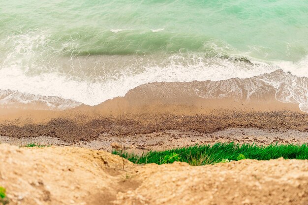 Vista superior del mar turquesa y espuma blanca, playa de arena y naturaleza marina