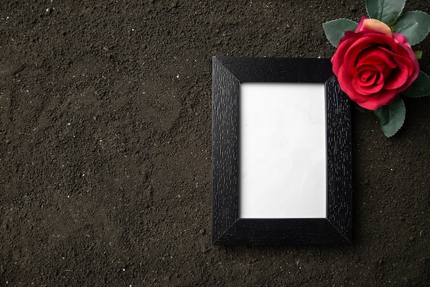 Foto vista superior del marco de imagen vacío con flor roja en suelo oscuro