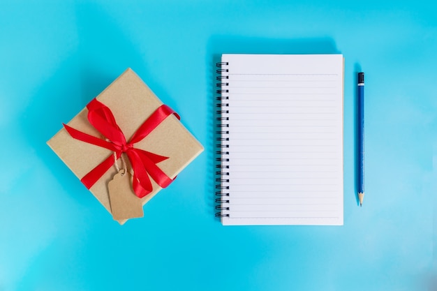 Vista superior marrón caja de regalo y papel de cuaderno para año nuevo en color azul pastel.