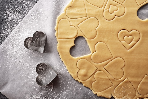 Vista superior de la masa de tarta con forma de corazón sobre fondo gris