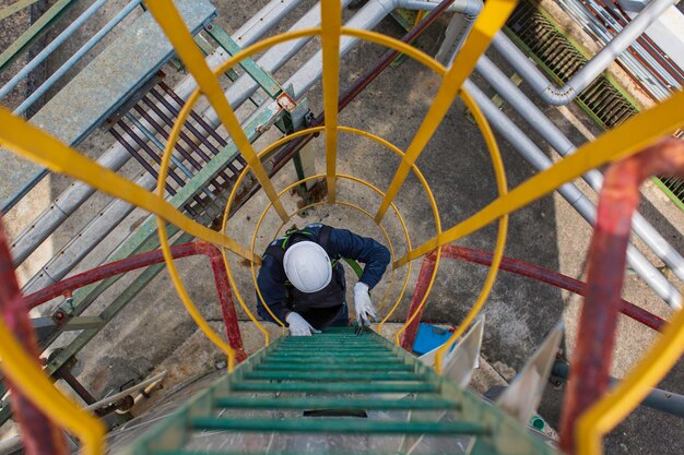 Vista superior masculina subir o óleo do tanque de inspeção visual de armazenamento de escada de escada