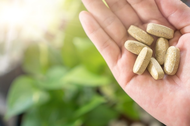 Vista superior de la medicina orgánica alternativa o la tableta de cápsulas de suplementos vitamínicos a base de hierbas en la mano de la mujer