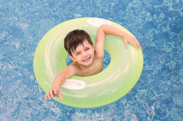 Vista superior menino na piscina com flutuador