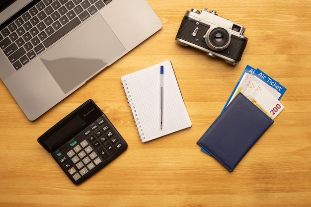 Vista superior de la mesa de escritorio de fotografía de oficina con computadora portátil, computadora portátil, cámara, calculadora y pasaporte con boleto aéreo.