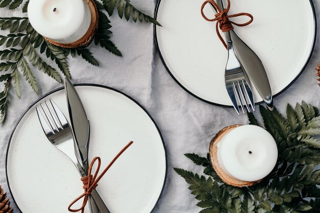 Vista superior de la mesa festiva para dos personas entre decoraciones de invierno y velas blancas El concepto de una cena familiar de Navidad o Acción de Gracias