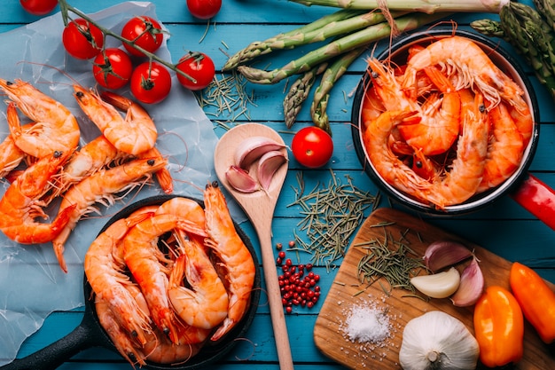 Vista superior de la mesa de madera azul llena de gambas y algunos ingredientes