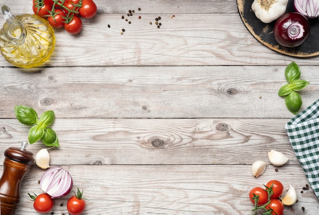 Vista superior de la mesa de madera para cocinar alimentos con verduras frescas, especias, hierbas y aceite de oliva.