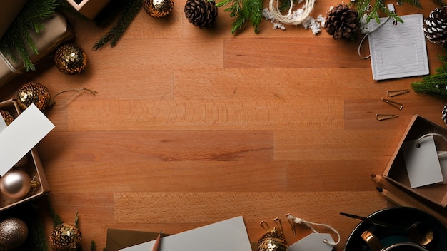 Vista superior de la mesa de madera con espacio de copia, simulacros de tarjetas de felicitación y decoraciones en concepto de Navidad