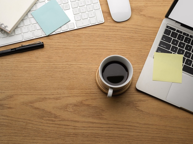 Vista superior de la mesa de madera con espacio de copia, taza de café para computadora portátil y artículos de papelería, escena creativa