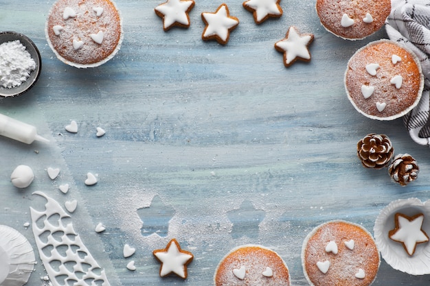 Vista superior de la mesa con panecillos espolvoreados con azúcar, glaseado de fondant y galletas de Navidad.