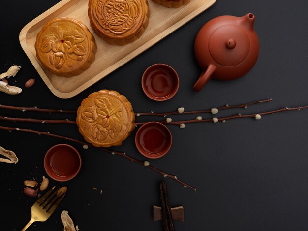 Vista superior de la mesa con pasteles de luna tradicionales, juego de té, decoración y espacio para copiar. El carácter chino en el pastel de luna representa "cinco almendras y cerdo asado" en inglés