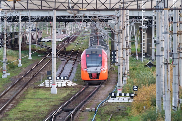 Vista superior del moderno tren interurbano de alta velocidad bajo el puente de transporte comercial