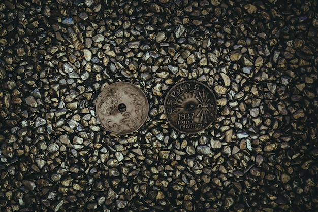 Vista superior de monedas y agujeros en ellas en las piedras pequeñas.