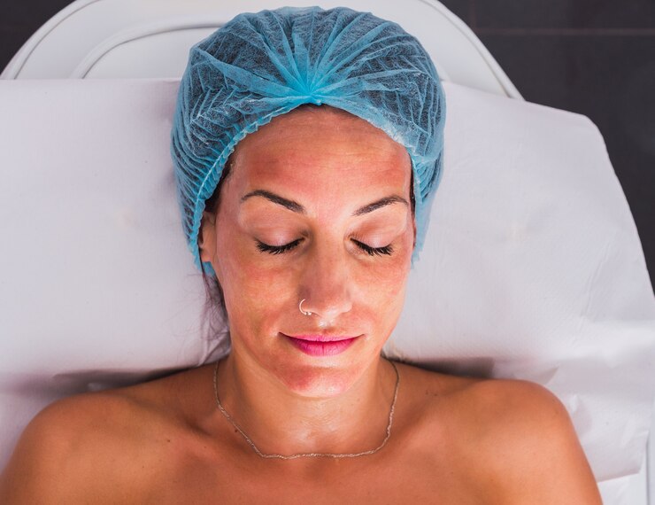 Vista superior de una mujer adulta con gorro médico desechable con una máscara dorada en el rostro para un tratamiento de belleza en el salón de spa.