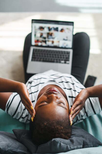 Vista superior de una mujer africana que tiene dolor de cabeza después de un montón de trabajo independiente de trabajo informático