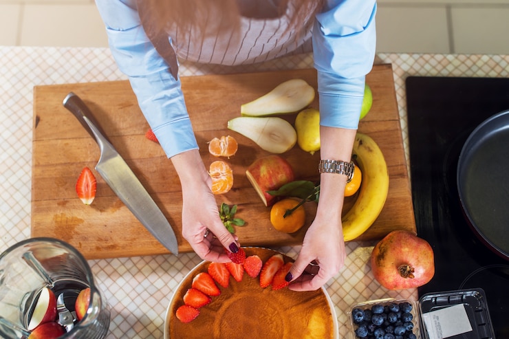 Foto vista superior de la mujer decorar una capa de pastel con fresa. ama de casa cocinando pastel de frutas