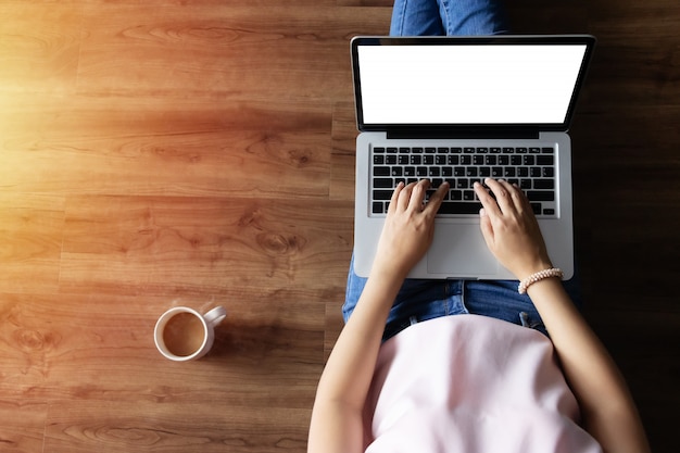 Foto vista superior de la mujer escribiendo en la computadora portátil con pantalla en blanco en blanco