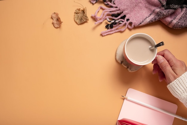 Vista superior de la mujer escribiendo en el cuaderno en blanco mano femenina escribiendo en el bloc de notas vacío con taza de café pla