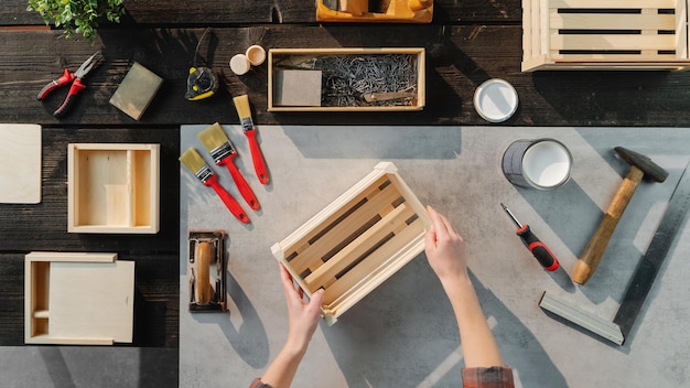 Una vista superior de una mujer irreconocible haciendo cajas de madera, pequeñas empresas y concepto de escritorio.