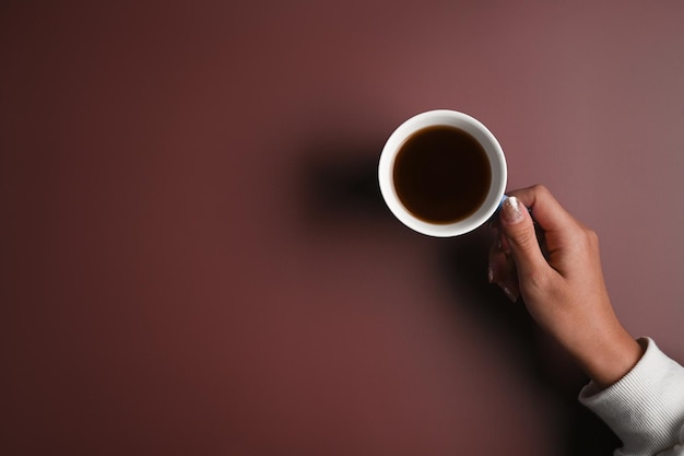 Vista superior mujer joven Han sosteniendo una taza de café sobre fondo púrpura