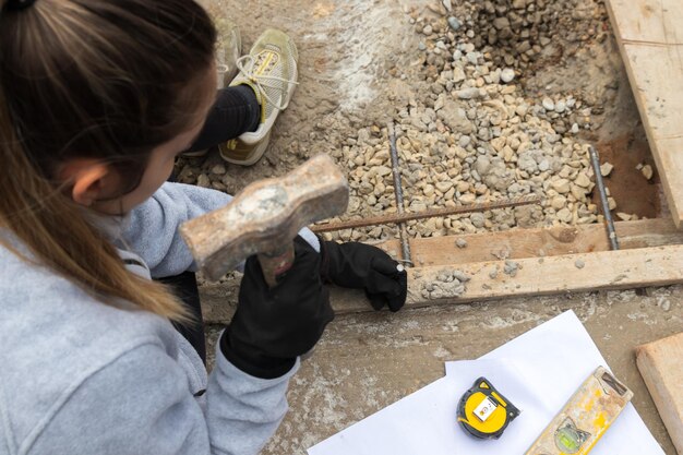 Foto vista superior de la mujer joven martillando un clavo en un sitio de construcción