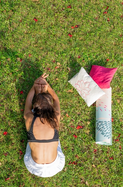 Vista superior de una mujer joven practicando yoga en un prado verde Sentada e inclinada hacia adelante Imagen vertical