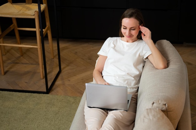 Vista superior de una mujer joven que usa su tableta mientras se relaja en el sofá