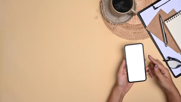 Foto vista superior de una mujer joven con un teléfono inteligente en su espacio de trabajo.