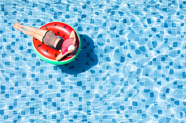 La vista superior de la mujer pone en el globo en piscina