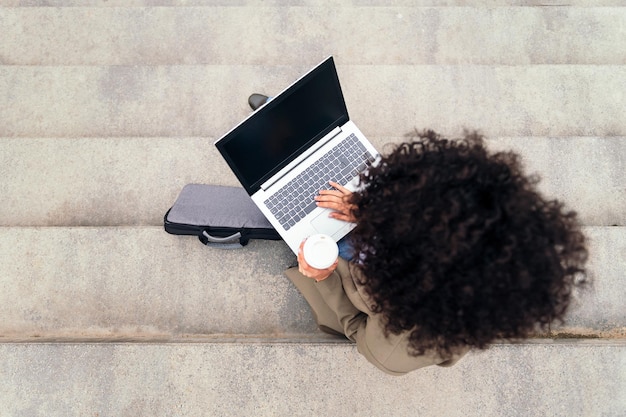 Vista superior de una mujer que trabaja al aire libre con computadora