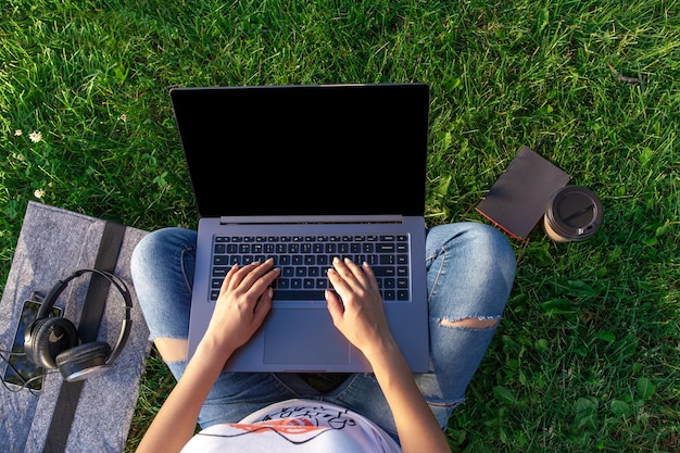 Vista superior de la mujer que trabaja en la computadora portátil con pantalla vacía en blanco negro para copiar el espacio en el parque en ...