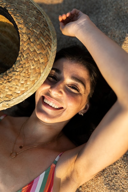 Vista superior mujer sonriente acostada en la playa