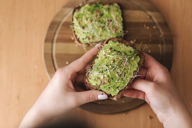 Vista superior de la mujer sostenga pan tostado de centeno con guacamole en la parte superior. Sin gluten