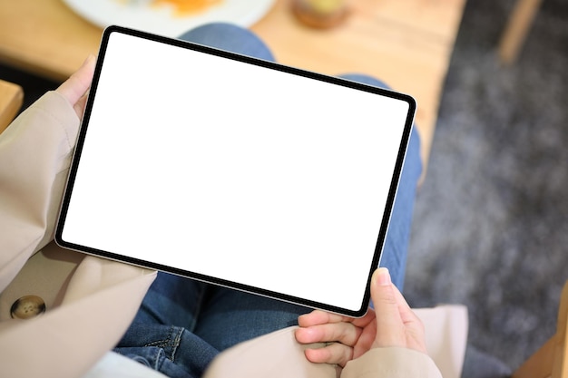 Vista superior Mujer sosteniendo una maqueta de panel táctil de tableta de pantalla en blanco sobre la mesa incluye trazado de recorte
