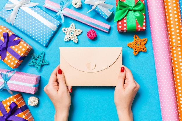 Foto vista superior de una mujer sosteniendo un sobre sobre fondo azul hecho de decoraciones navideñas concepto de tiempo navideño