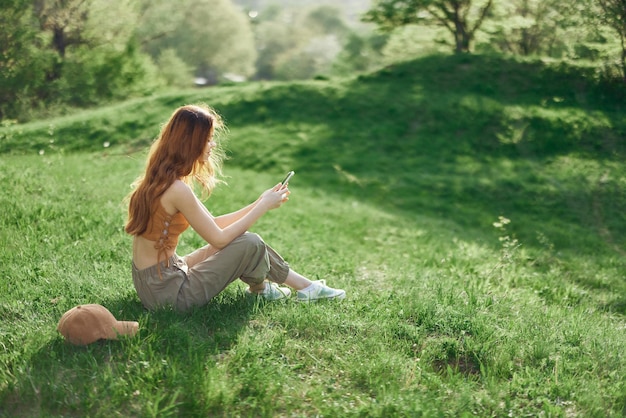 Vista superior de una mujer con teléfono en mano estudiante independiente tratando de encontrar conexión a Internet en la naturaleza en un parque de verano verde