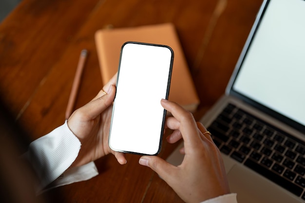 Vista superior de una mujer usando su teléfono inteligente mientras está sentada en su escritorio