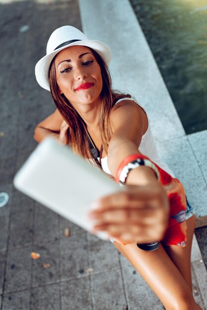 Vista superior na linda mulher de férias tomando selfie com seu telefone inteligente. Foco seletivo.