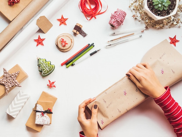 Foto vista superior na mesa com decorações de natal mulher desenha símbolos de ano novo em presentes de artesanato