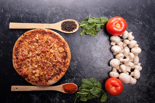 Vista superior na pizza recém-assada ao lado dos ingredientes feitos na mesa de madeira escura